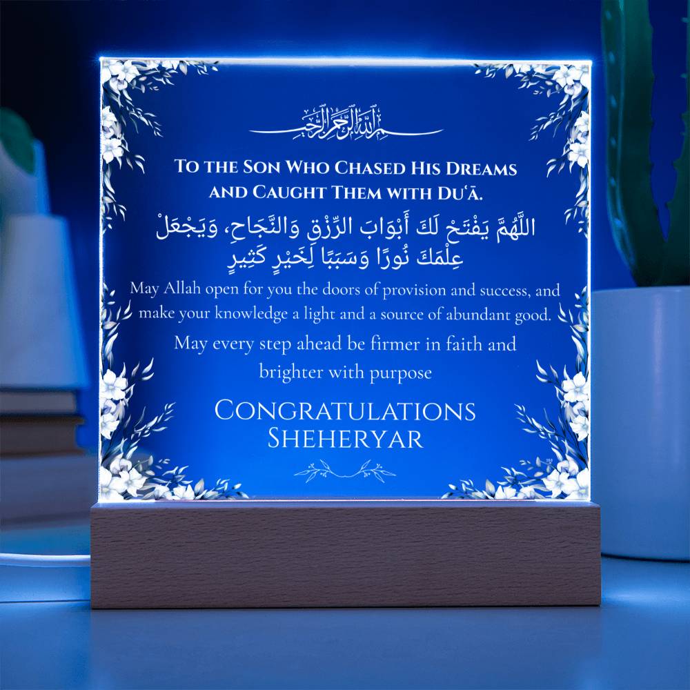 a blue and white rectangular plaque with Arabic text and English text, placed on a wooden stand.